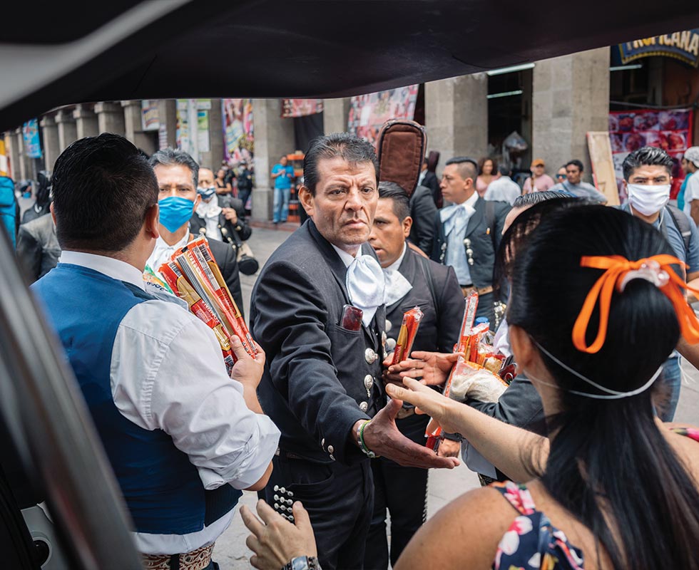 A musician shakes hands with a volunteer who handed out food and supplies in Plaza Garibaldi.